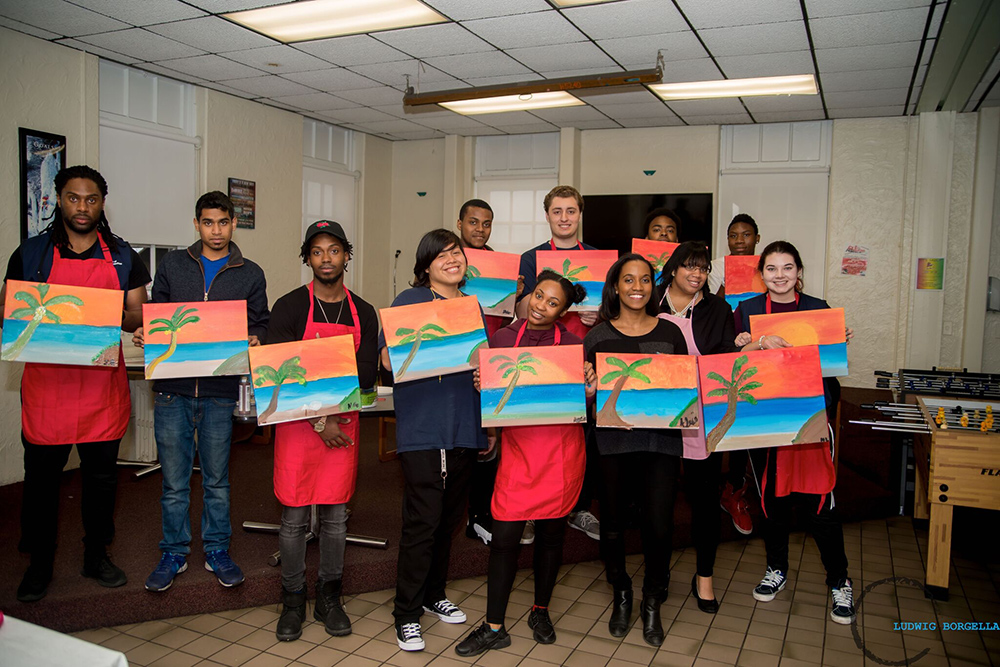 Students holding their paintings done during a game room event 